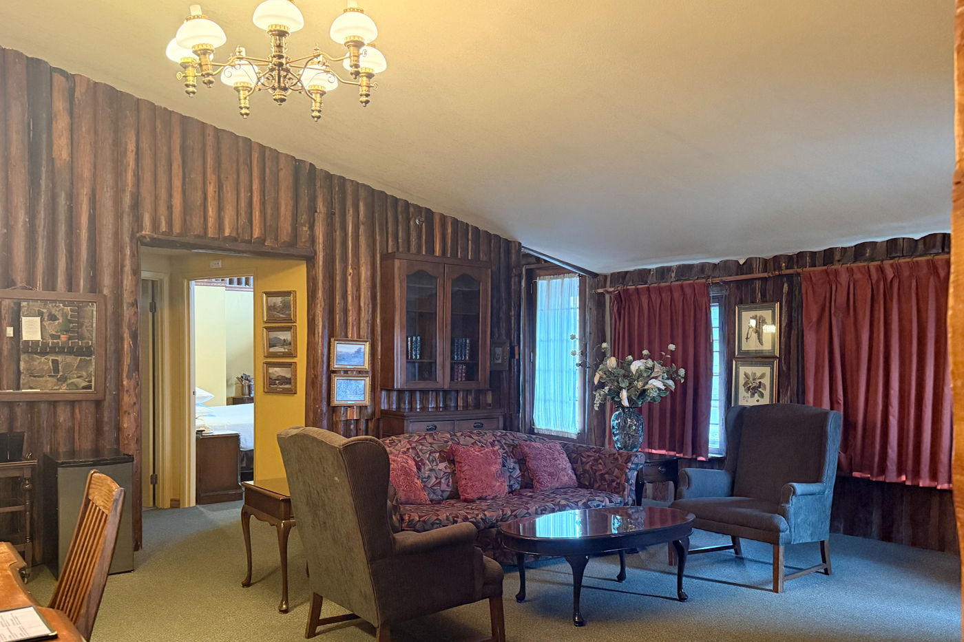 Deluxe suite living room at The Riverview Lodge with log walls, a sofa, and a view toward the river